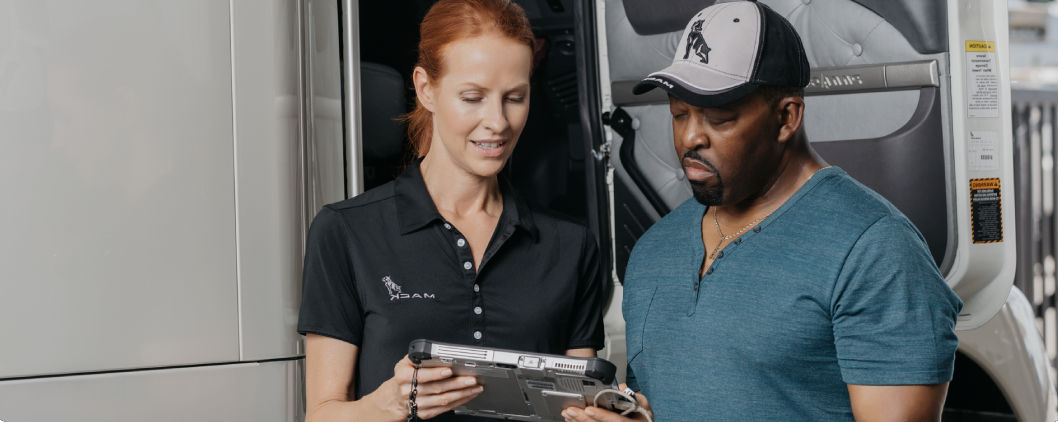 Woman and man discussing on a tablet next to a truck